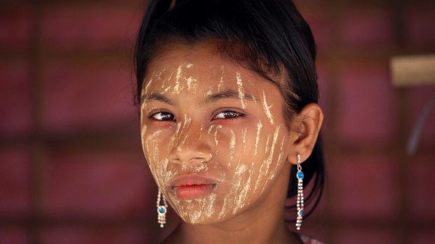 A Rohingya girl with her face covered in 'thanaka', a comestic paste from ground bark, stands in her family's tent in Kutupalong refugee camp in Bangladesh.