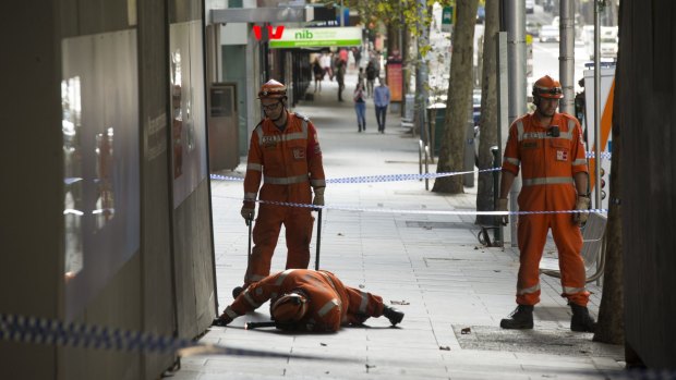 Police and SES search for a mobile phone along Collins Street on Friday. 