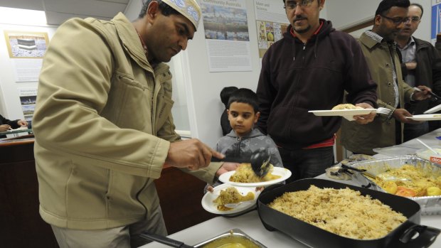 Rahimat Ali feeds son  Rehan, 7, at the breaking of the fast for Ramadan at the Ahmadiyya Muslim Association Canberra branch in Fyshwick.
