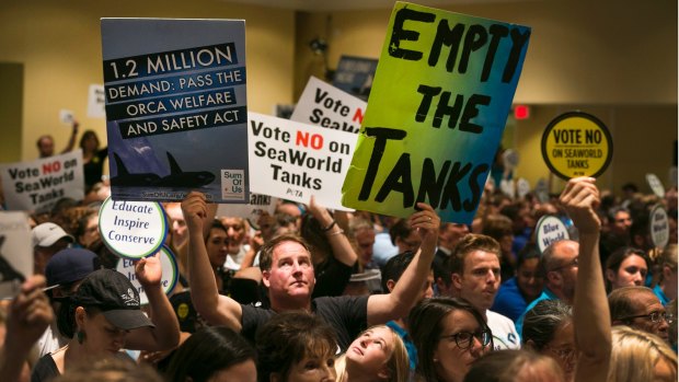 Animal rights activists hold up signs during a California Coastal Commission meeting in Long Beach, California.