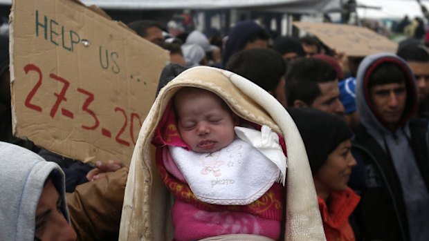 A migrant holds a baby during a protest demanding the opening of the border between Greece and Macedonia on Sunday. 