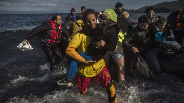 Fiorella Crotti, a member of Spanish rescue group Proactiva Open Arms, carries a child as migrants and refugees disembark from a dinghy after crossing the Aegean Sea from Turkey to the Greek island of Lesbos. 