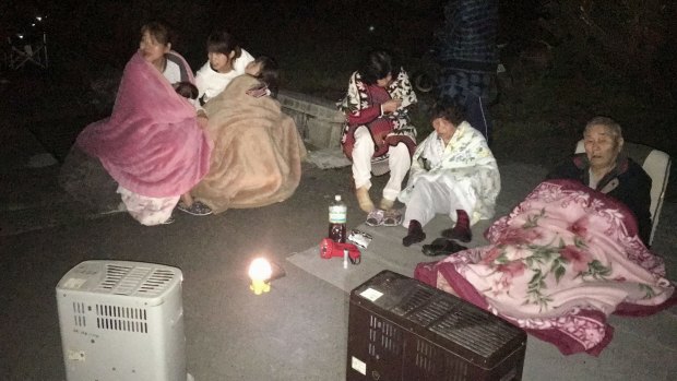 Residents wrap themselves in blankets on road in Mashiki.