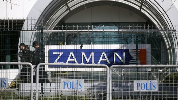Riot police officers walk by the headquarters of <i>Zaman</i> newspaper in Istanbul after it was shut down.