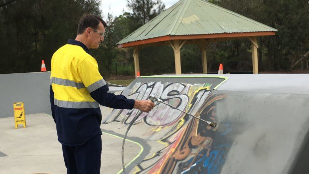 Lord Mayor Graham Quirk paints over graffiti at the council's Stafford Heights skate park.