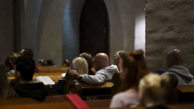 People attend a prayer service for stabbing victims at the Cathedral in Turku, Finland.