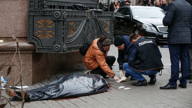 Forensic experts and police officers examine the scene following the killing of Denis Voronenkov in Kiev, Ukraine.