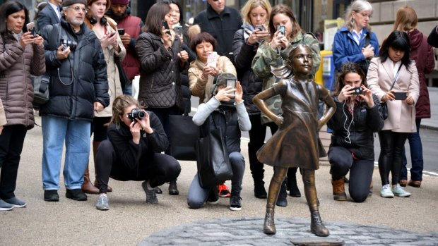 Onlookers admire The Fearless Girl statue in Manhattan.