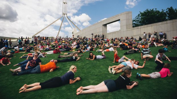 Hundreds roll down the lawns of Parliament House in a protest against plans to fence off the area.