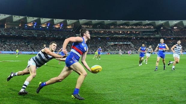Opening night: Bulldog Bailey Williams looks to handball on Friday night with Geelong’s new Brownlow Stand in the background. 