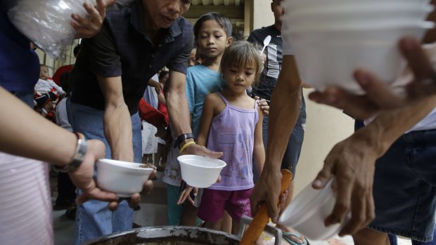 Evacuated children receive free chocolate rice porridge as they seek shelter at an evacuation centre.