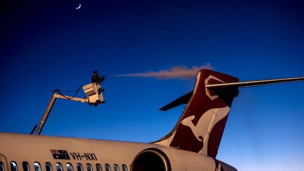 An engineer removes ice from a Qantas aircraft at Canberra airport in sub-zero temperatures.