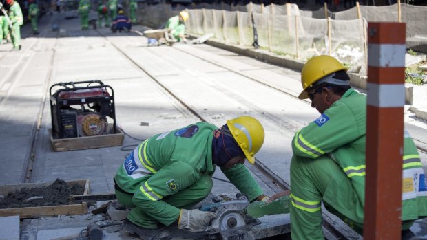A worker cuts paving stones during construction of a light rail system in downtown Rio last month.