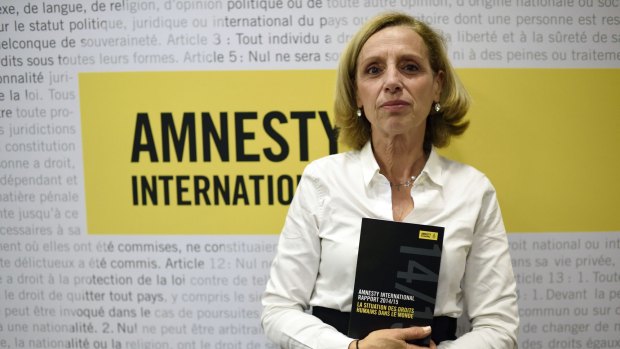 Amnesty International France President Genevieve Garrigos holds a copy of the 415-page annual report, which details abuses in 160 countries. 