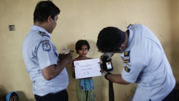 Indonesian immigration officials take photos of an ethnic Rohingya girl upon her arrival at a temporary shelter in Lapang.