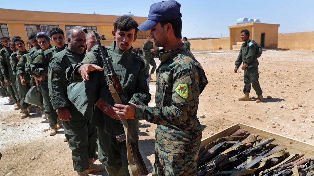 Syrian Internal Security Forces receive weapons during their graduation ceremony, at Ain Issa desert base, in Raqqa on Thursday. Some 250 residents of Raqqa are the latest batch to graduate from a brief US-training course.