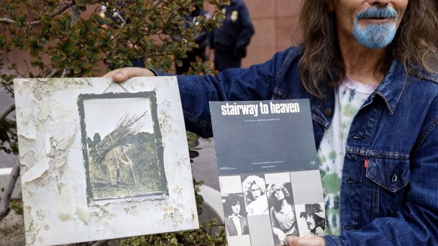 A Led Zeppelin fan holds up an album and sheet music for <i>Stairway to Heaven</i> outside federal court in LA. 