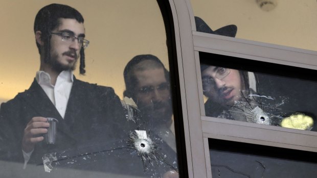 Jewish religious students examine bullet holes in the aftermath of the Har Nof synagogue attack in Jerusalem.