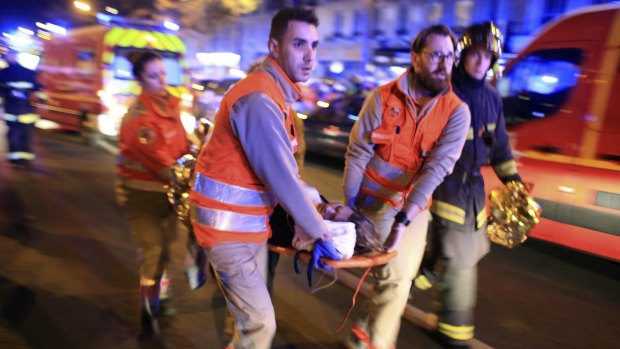 A woman is evacuated from the Bataclan theatre in Paris on Friday night after more than 100 people were killed in a terrorist attack. In total more than 150 people died in attacks across the French capital.