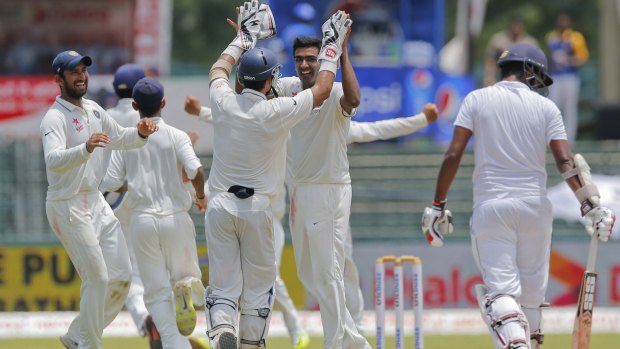 India's off-spinner Ravichandran Ashwin high-fives wicketkeeper Naman Ojha after dismissing Lahiru Thirimanne.