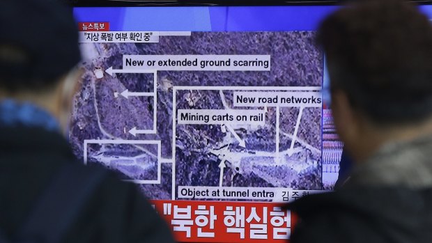 People watch a TV screen showing reports about an 'earthquake' near the test site.