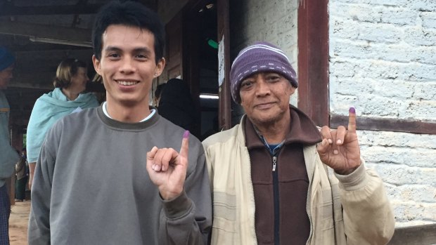 Men from different generations display their inked fingers after voting.