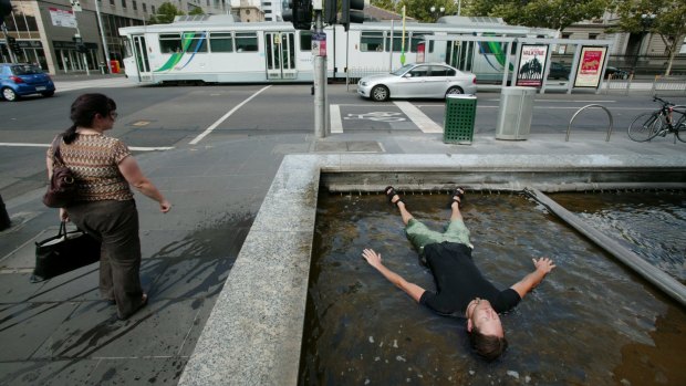 A man dives into a fountain on Wednesday as warm weather takes hold of Melbourne.