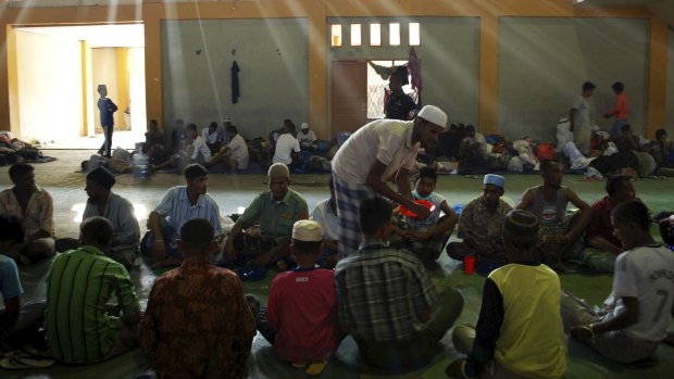 Rohingya and Bangladeshi migrants receive food inside a temporary shelter in Lhoksukon in Aceh.