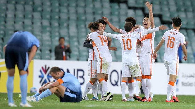 Down and out: Shandong Luneng players celebrate as Sydney FC players slump to the ground at the final whistle.