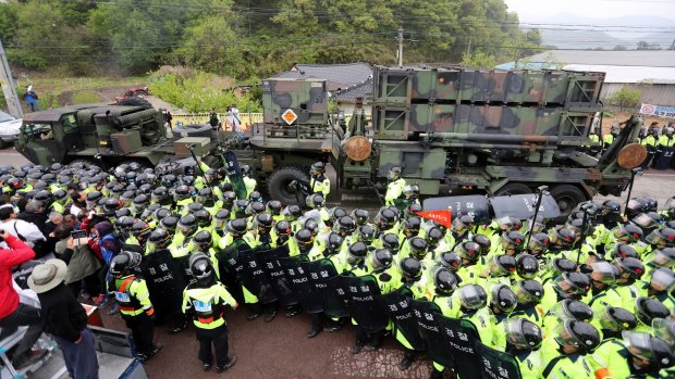 South Korean police protect a US military vehicle from protesters who oppose a plan to deploy the THAAD system against North Korean attack.