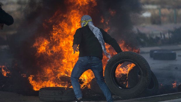 A Palestinian protester burns tires during clashes with Israeli troops.