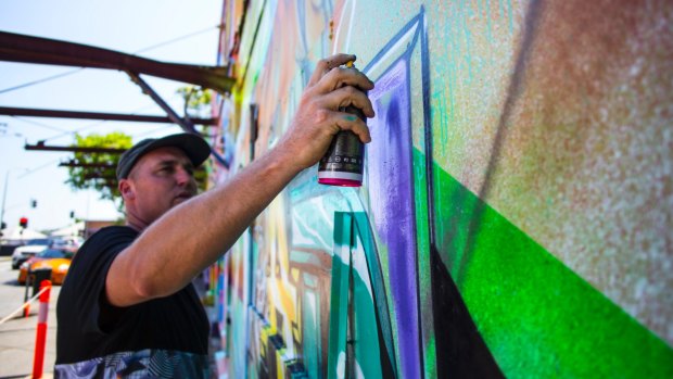 Street artist Drapl creating a piece at the Old Brisbane Skate Arena as part of Brisbane Street Art Festival.