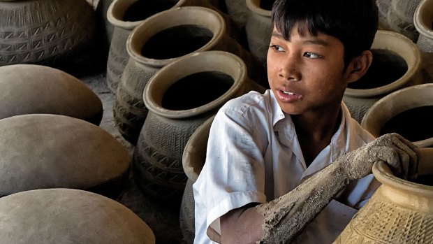 A boy helps to make traditional pottery in  Mandalay Myanmar.