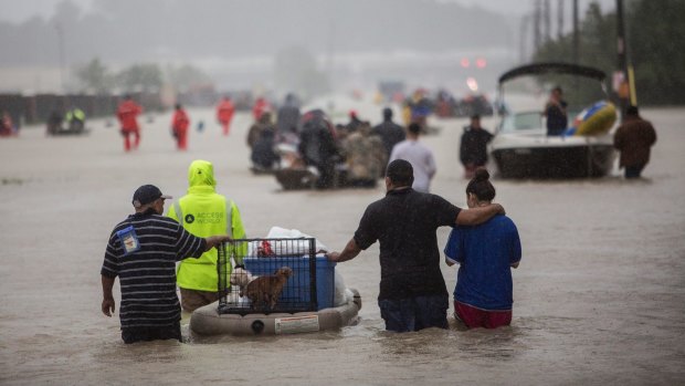 First responders and volunteer rescuers help evacuate people stranded by floodwaters on the outskirts of Houston.