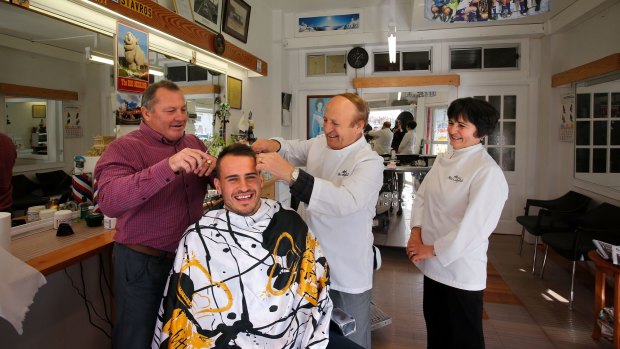 Shearing time: Bulldogs legend  Terry Lamb, left, gives Josh Reynolds a trim with the help of local supporters and barbers, Steve and Tonia Balafas.