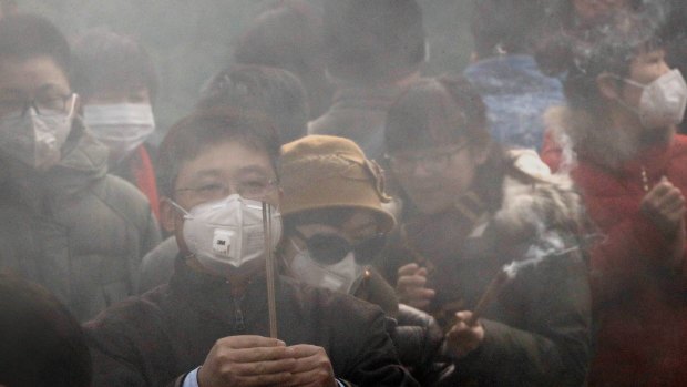 Chinese worshippers wearing masks burn incense while offering prayer at Beijing's Yonghegong Lama Temple as the Chinese capital is blanketed by heavy smog on the first day of the New Year.