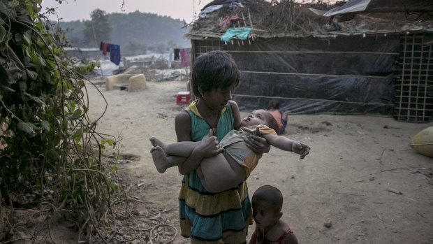 A girl carries a toddler in Bangladesh. A one-metre rise in sea level would submerge one-fifth of the country, displacing 30 million people.