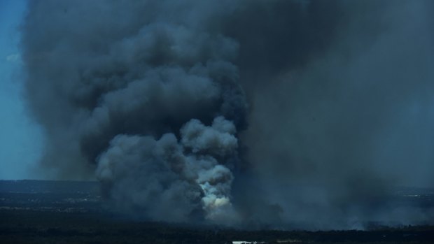 Thick black smoke erupts from the out of control bushfire.