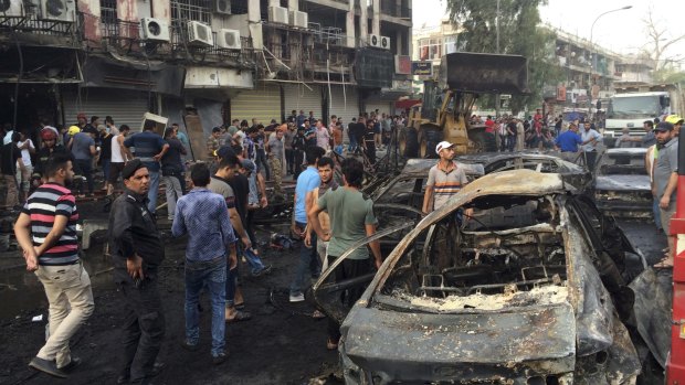 Iraqi security forces and civilians gather at the site after a car bomb exploded in a Baghdad commercial district.