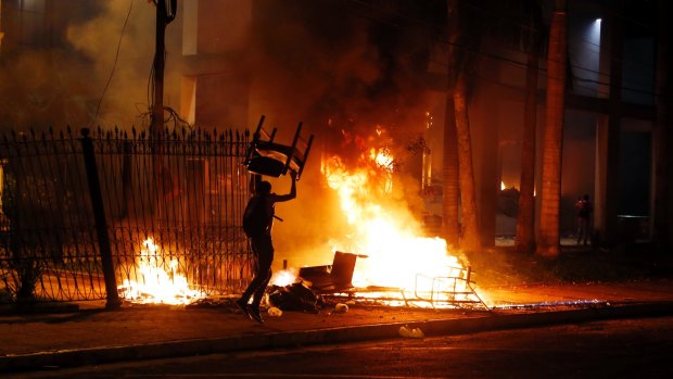 A protester carries a chair to a fire outside the Congress building in Asuncion, Paraguay, on Friday, March 31, 2017.