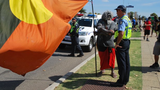 A police officer greeting Nyoongar man Herbert Bropho during a peaceful protest on Australia Day. 