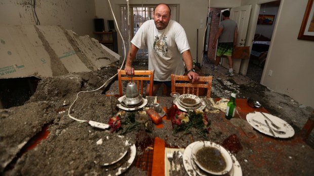 Just yesterday this house sold at auction for a record price. Frank Partic stands at a set dinning table amongst ruins.