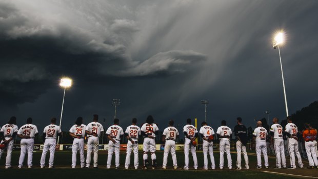 Canberra Cavalry players line up during a moment of respite from the weather.