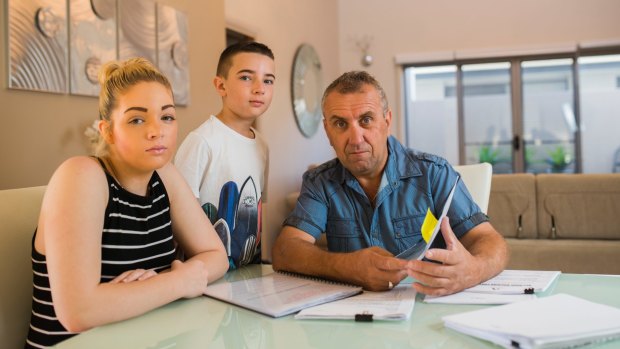 Chantelle, Ethan (10), and John Ireland at their home in Forde which has scructural damage QBE Insurance is refusing to cover.
