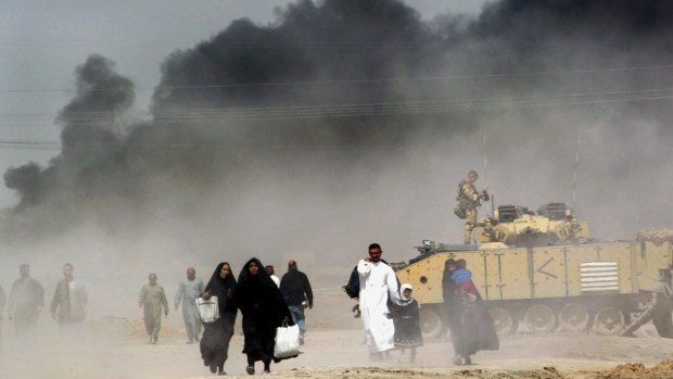 The war: Iraqis pass by a British tank as they flee Basra in 2003.