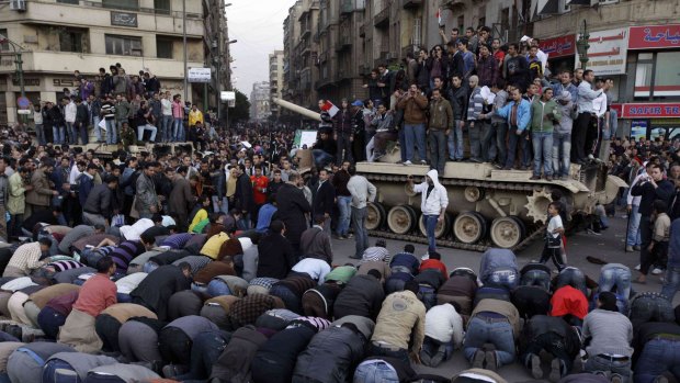 Egyptian anti-government protesters pray in front of a tank in Cairo's Tahrir Square in January 2011.