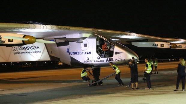 The ground crew pushes Solar Impulse 2 as pilot Andre Borschberg sits in the cockpit at Nagoya Airport.
