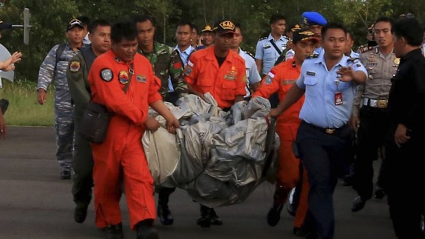 Rescue workers carry debris recovered from the ocean, presumed to be part of the AirAsia plane.