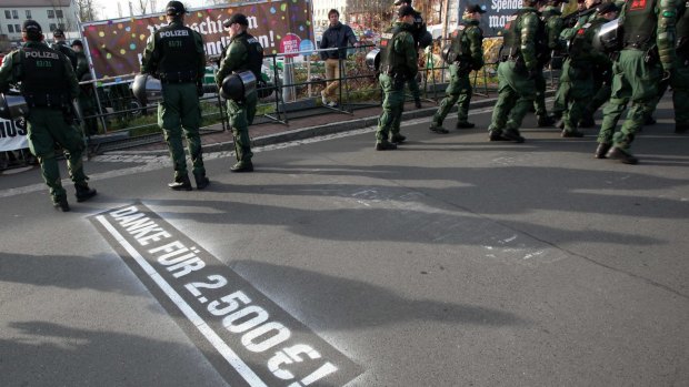 A sign on the street thanks the neo-Nazis for €2.50 as they march under the watchful eye of police in Wunsiedel.