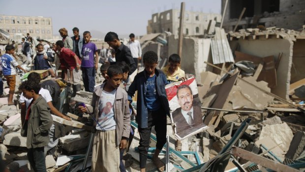 A boy holds a poster of former Yemeni leader Ali Abdullah Saleh at the site of shops destroyed by a Saudi-led airstrike in Sanaa.